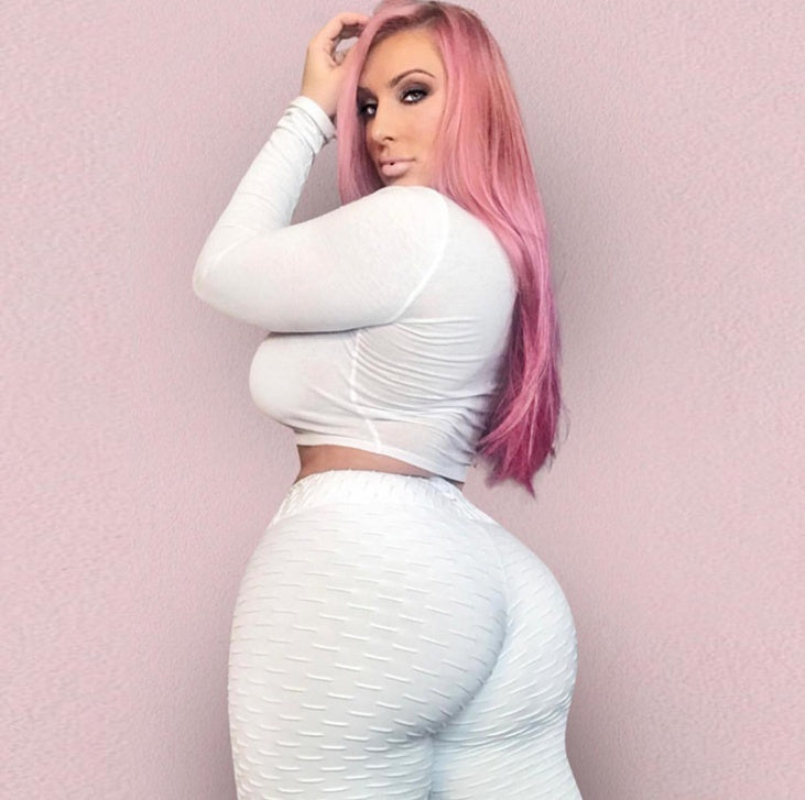 Woman with pink hair wearing a white outfit against a pink background