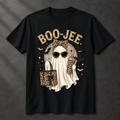A black short-sleeve graphic T-shirt laid flat on a dark textured background. The front print reads "BOO-JEE" in a leopard-print font above a ghost illustration wearing leopard-print sunglasses and holding a matching leopard-print tote bag.