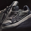 Black and gray sneakers with a reflective label on a black background