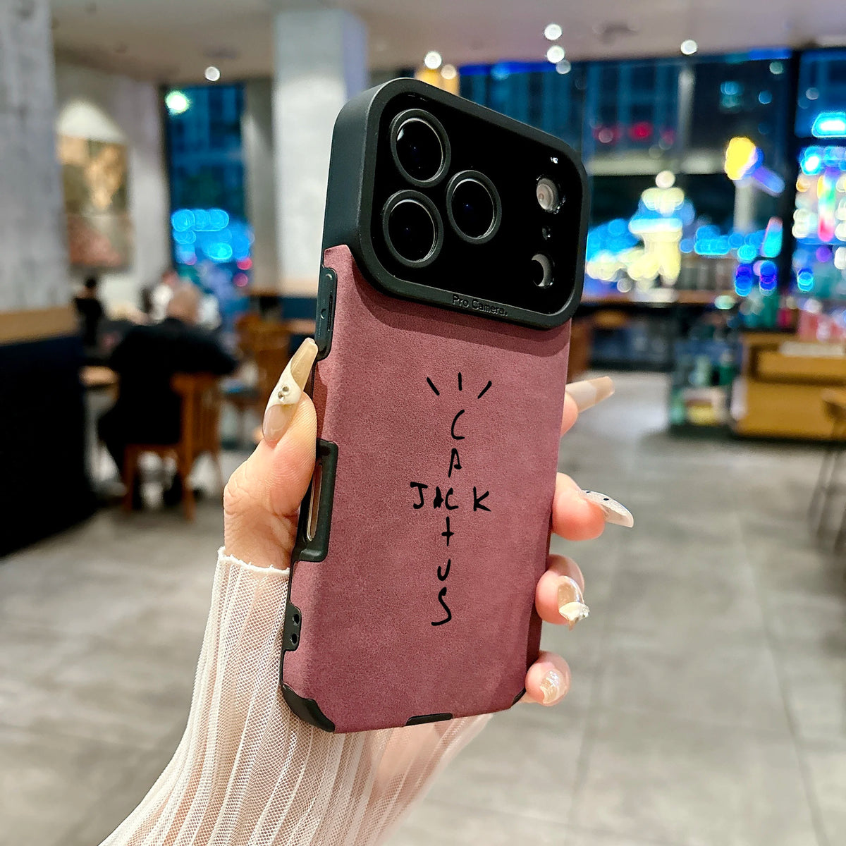 Hand holding a phone with a pink case in an indoor setting