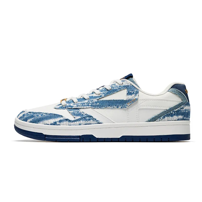 A low-top sneaker featuring a white leather base with blue distressed denim-like overlays, white laces, a white midsole with a dark blue outsole, and a small gold accent near the lace area.