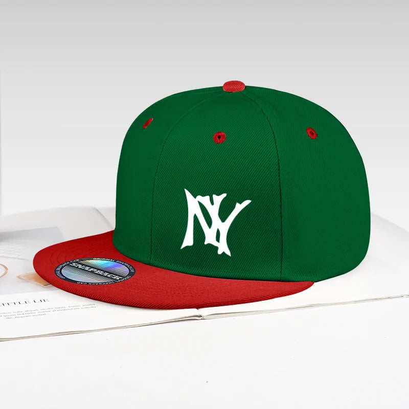 A green and red snapback cap with a white embroidered 'NY' logo on the front, displayed on a white surface with an open book underneath.