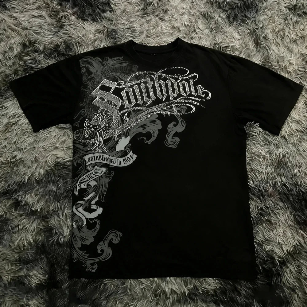 Black t-shirt with intricate silver design on a textured gray surface