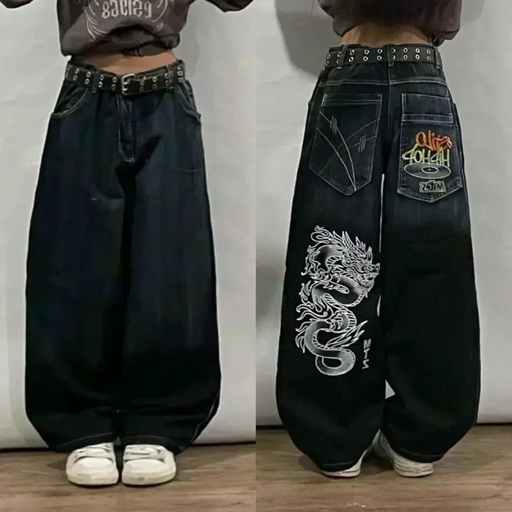 Black baggy jeans with dragon design and brand logo on a plain background