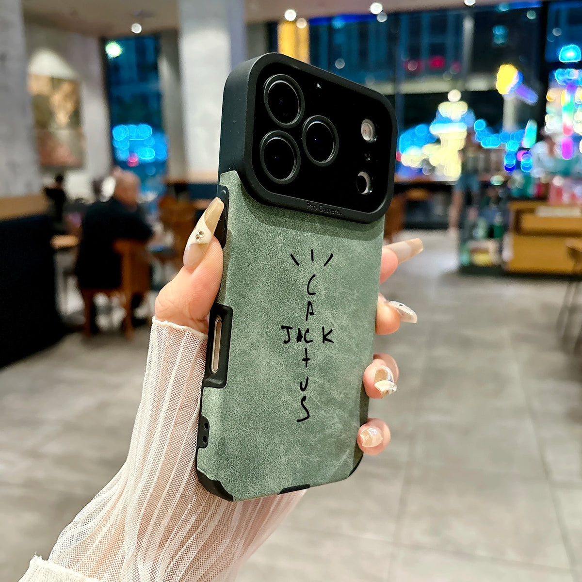 Hand holding a phone case with 'Cactus Jack' branding in an indoor setting.