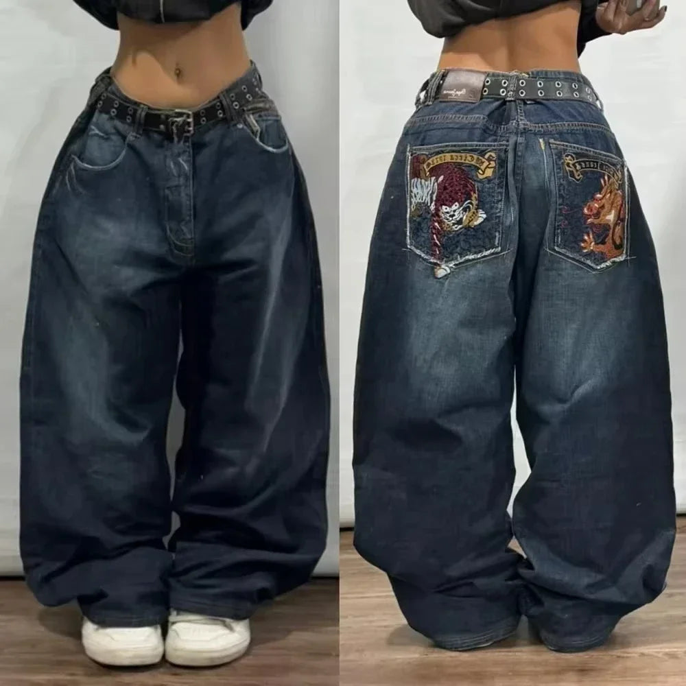 Pair of blue jeans with embroidered designs on the back pockets, worn by a person.