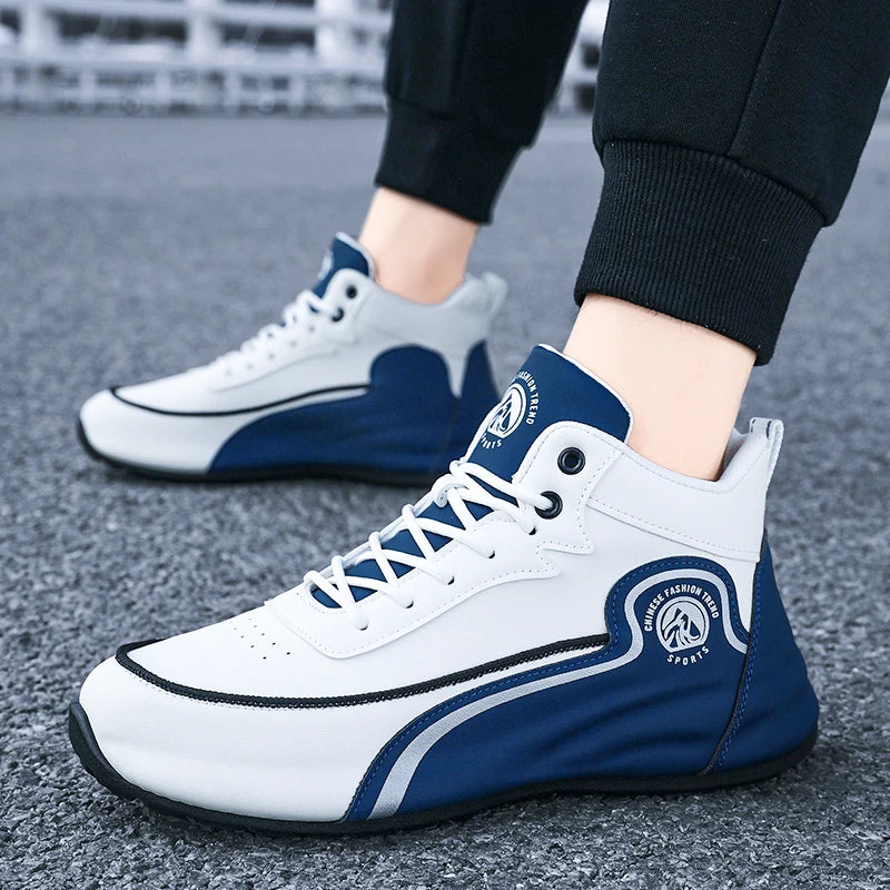 White and navy blue mid-cut athletic sneakers with black trim, shown on a person wearing black pants on a gray asphalt surface.