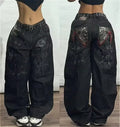 Black wide-leg pants with decorative patches worn by a person on a wooden floor.