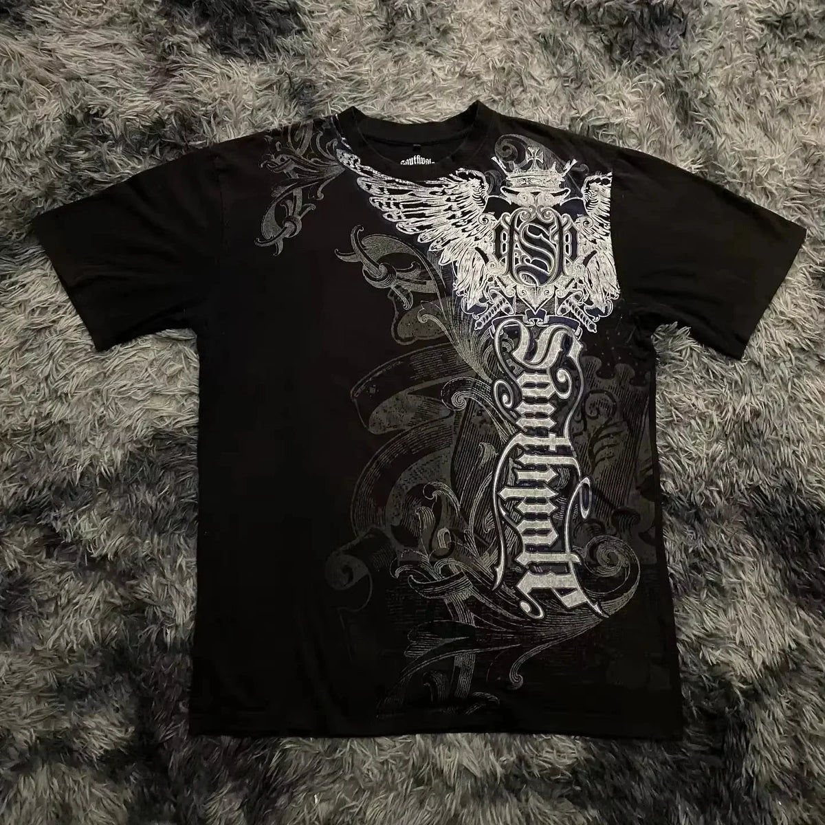 Black t-shirt with intricate white designs on a textured gray surface