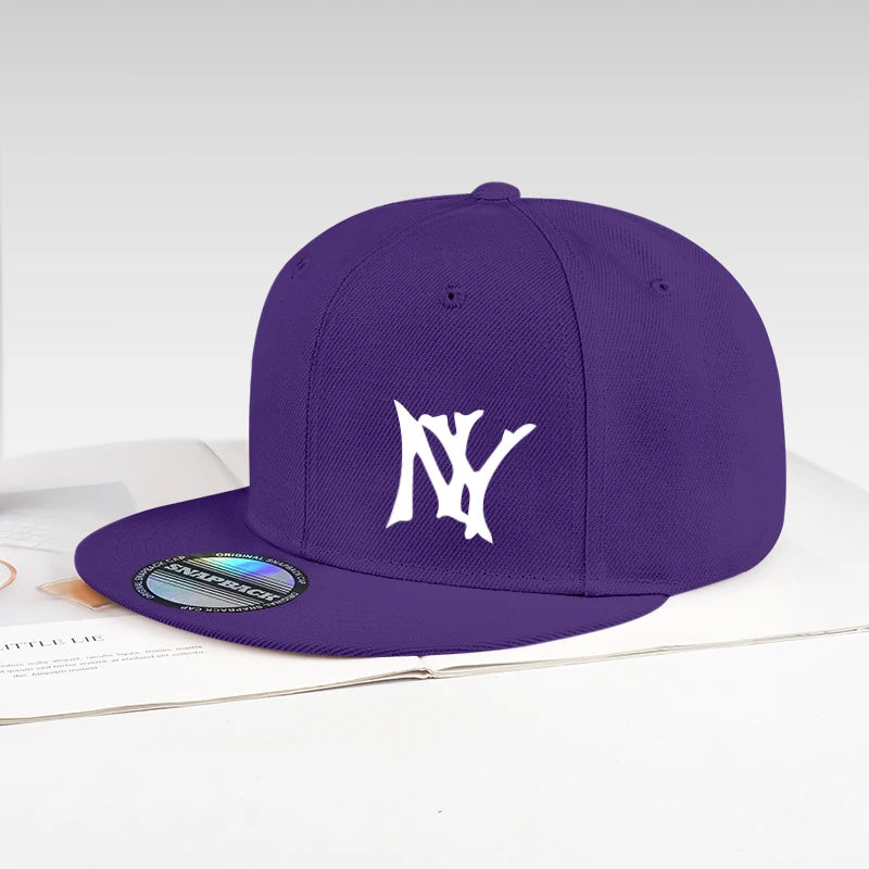 A purple flat-brim baseball cap with a white embroidered 'NY' logo on the front, resting on an open book against a light gray background.