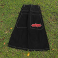 Black pants with a red and white design on the pocket laid on grass