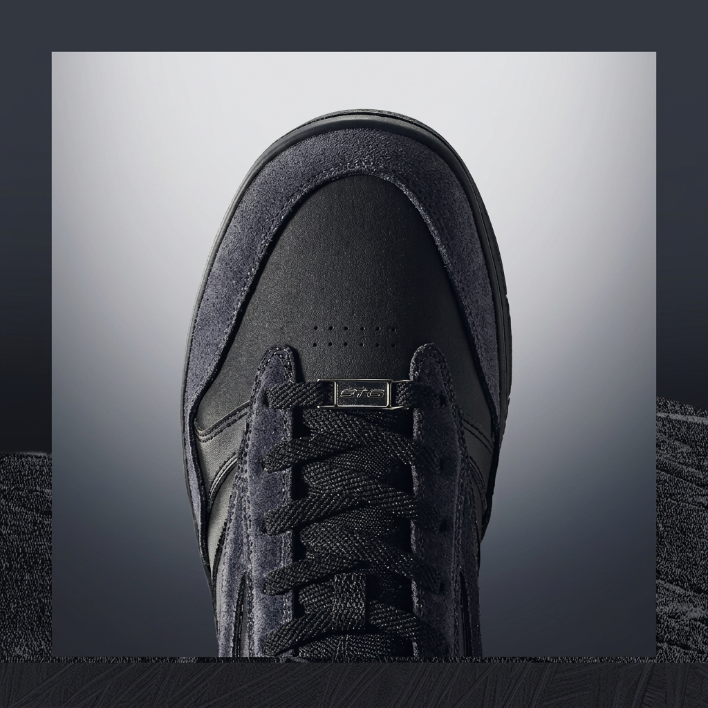A close-up top-down view of a black suede and mesh sneaker, centered against a dark gray gradient background with a textured dark border.