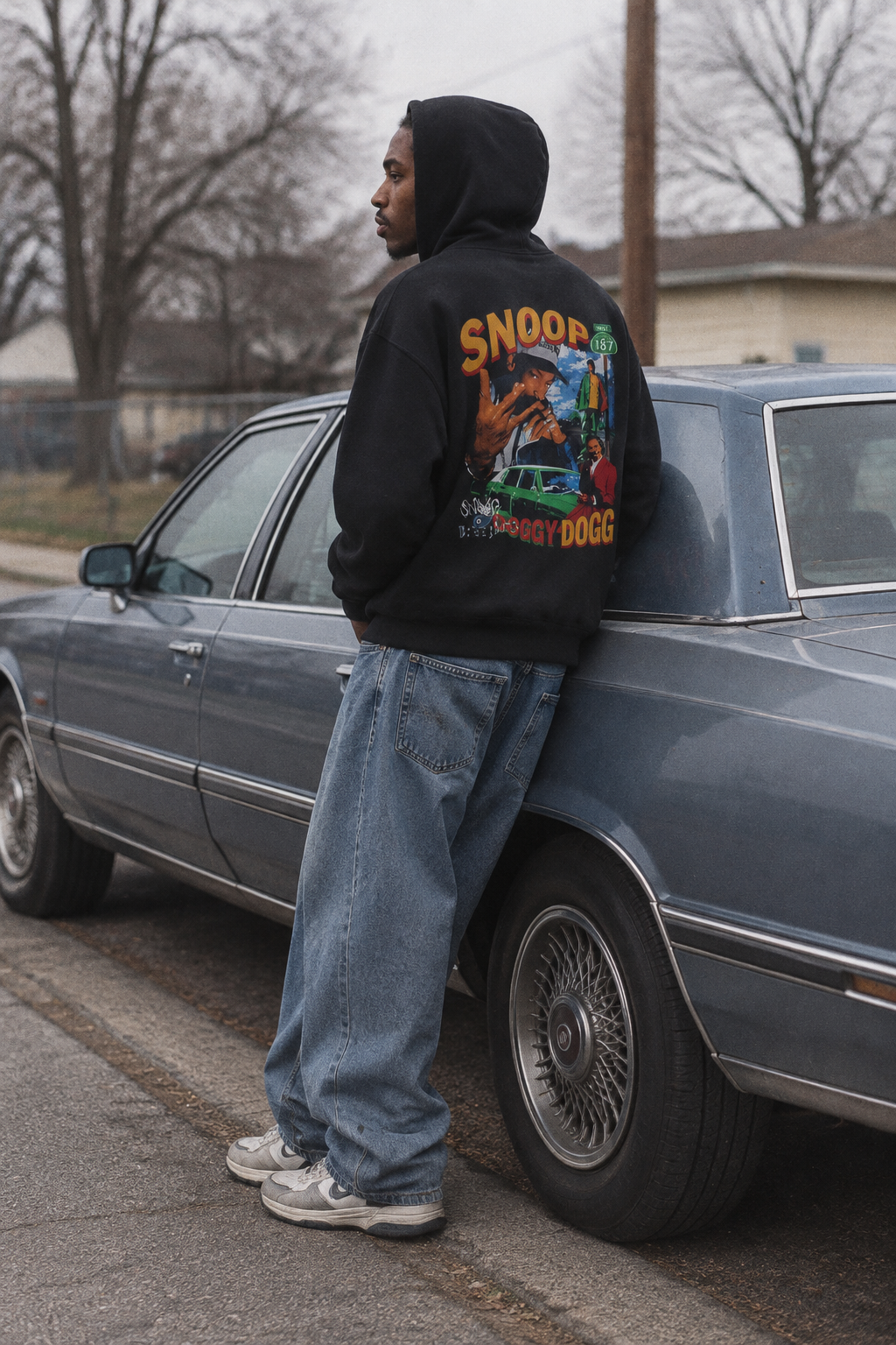 Person wearing the Snoop Dogg graphic hoodie in Color 2 beside a parked sedan in soft daylight.