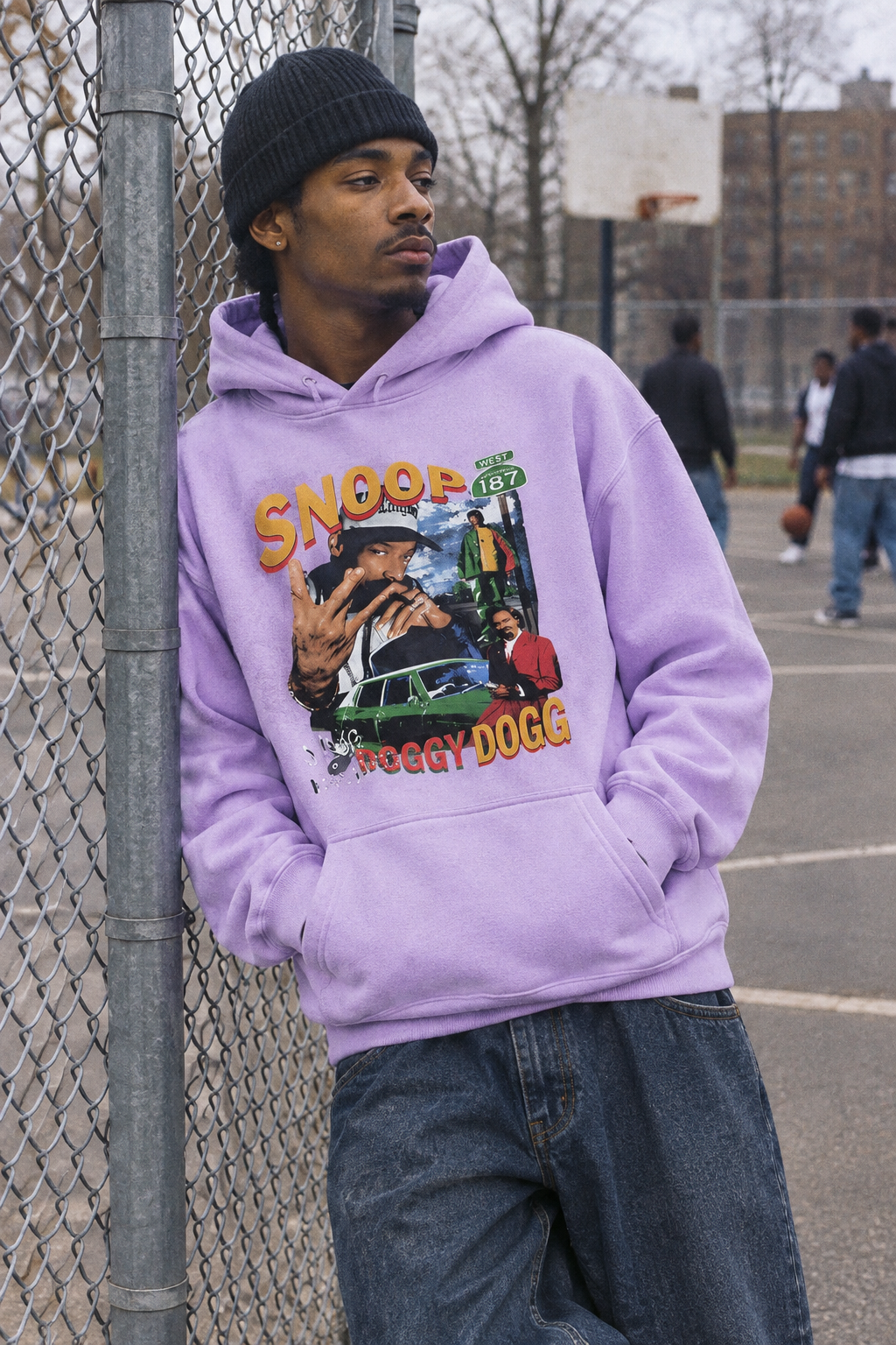 Person wearing the Snoop Dogg graphic hoodie in Color 6 beside a chain-link fence near a basketball court.