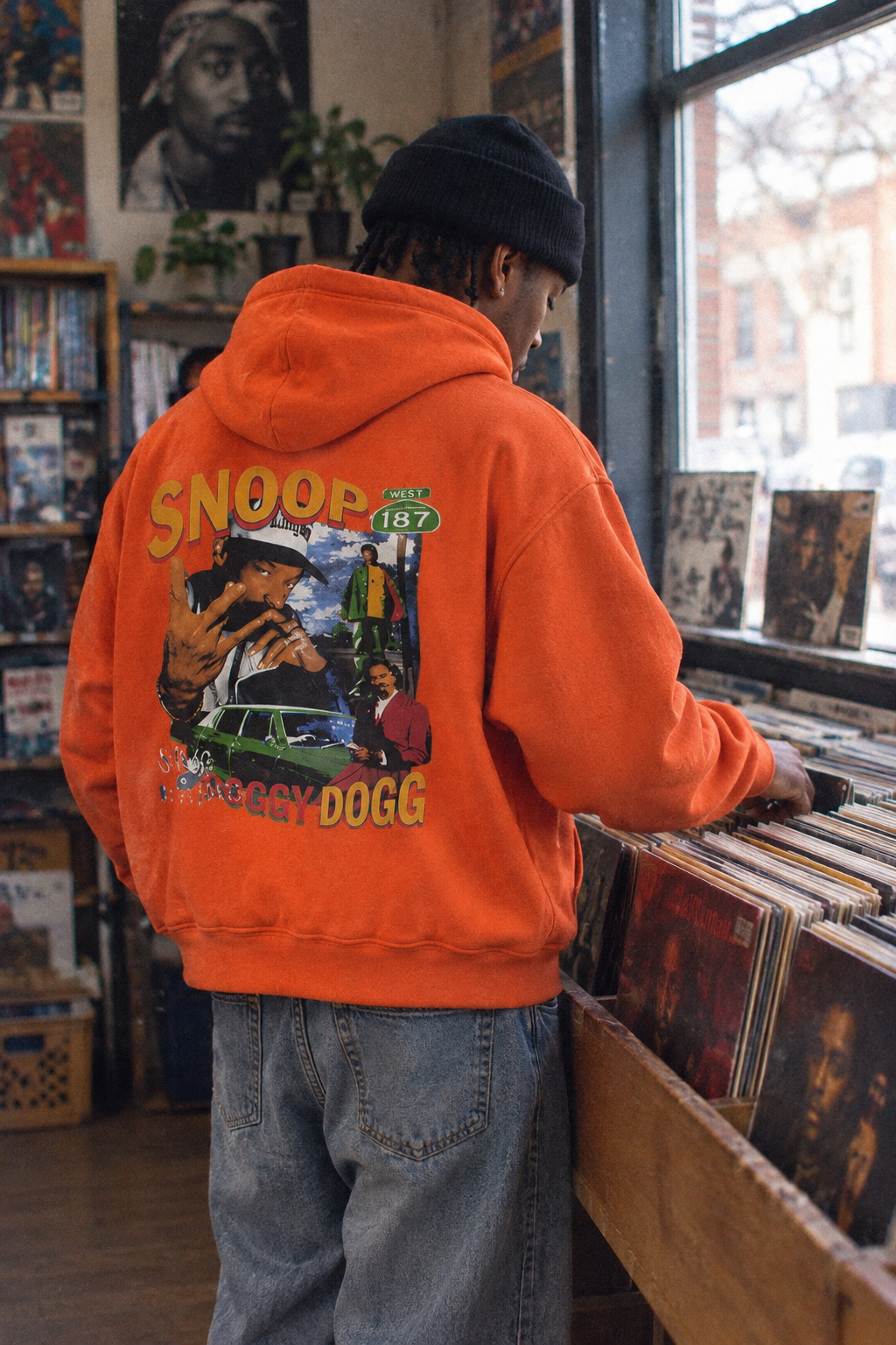 Person wearing the Snoop Dogg graphic hoodie in Color 7 browsing records in an independent record shop.