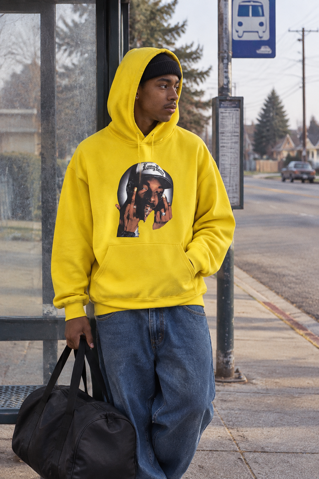 Person wearing the Snoop Dogg graphic hoodie in Color 10 at a neighborhood bus stop in natural morning light.