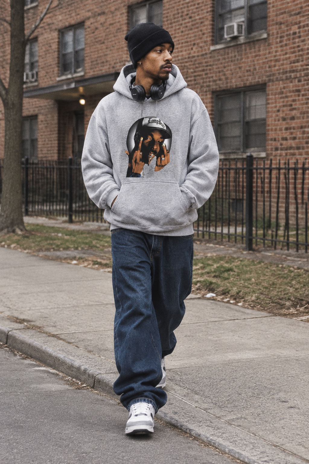 Person wearing the Snoop Dogg graphic hoodie in Color 5 outside a brick apartment building in cloudy daylight.