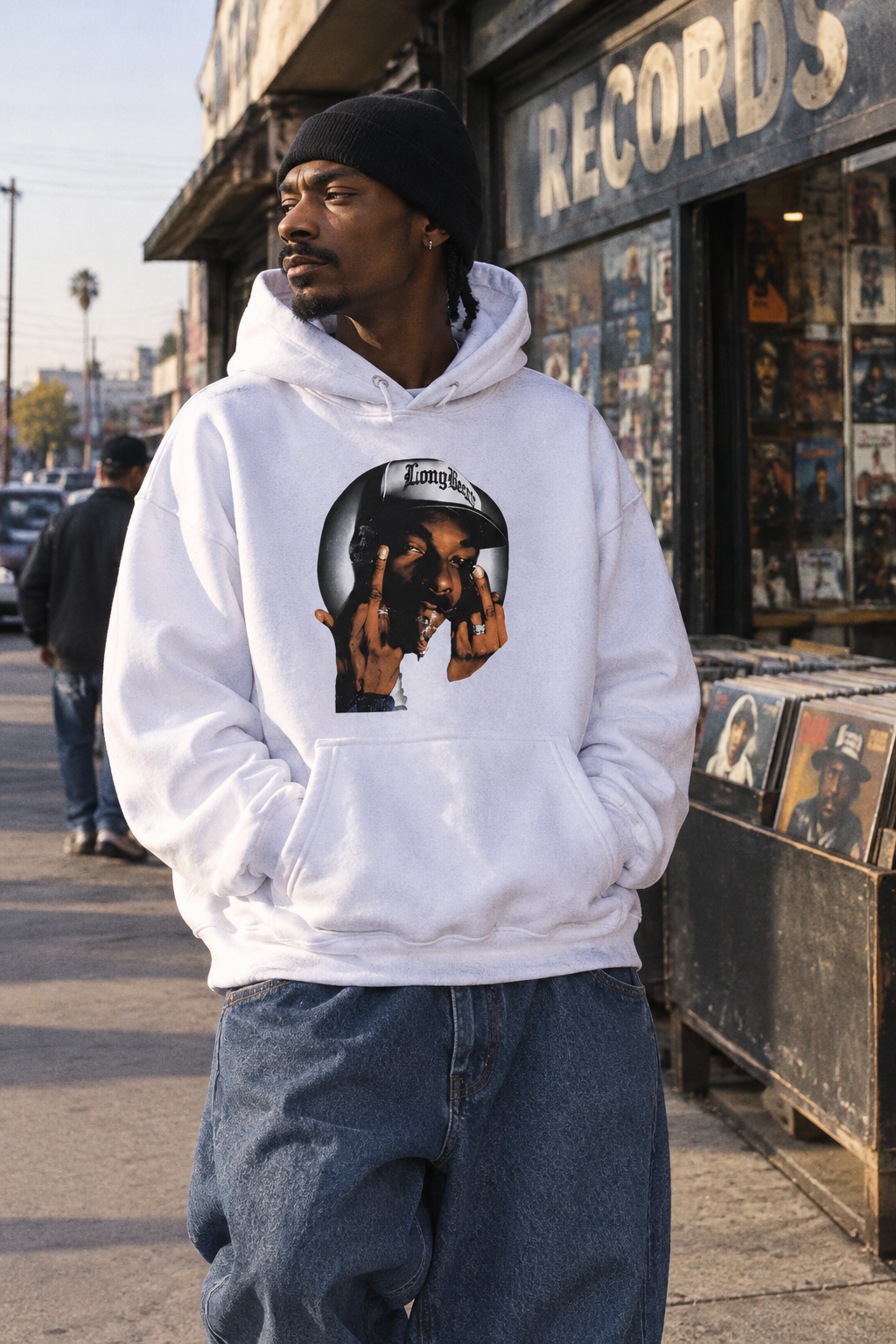 Person wearing the Snoop Dogg graphic hoodie in Color 1 outside a neighborhood record store in natural daylight.
